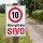 Das Bild zeigt ein Verkehrsschild, das eine Geschwindigkeitsbegrenzung von 10 km/h anzeigt und darauf hinweist, dass hier die Straßenverkehrsordnung (StVO) gilt. Es ist an einem Holzpfahl befestigt und steht an einem schmalen, unbefestigten Weg, um Verkehrsteilnehmer auf die geltenden Regeln aufmerksam zu machen.
