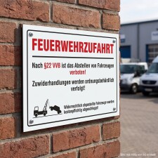 Das Bild zeigt ein Schild mit der Aufschrift FEUERWEHRZUFahrt in großen roten Buchstaben, das an einer Ziegelwand befestigt ist. Das Schild informiert, dass das Abstellen von Fahrzeugen in diesem Bereich verboten ist und dass Verstöße ordnungsbehördlich verfolgt werden.