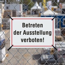 Das Bild zeigt ein Schild mit der Aufschrift „Betreten der Ausstellung verboten!“, das an einem Zaun befestigt ist. Es befindet sich in einem Bereich, der offensichtlich für die Öffentlichkeit gesperrt ist, möglicherweise um Sicherheitsrisiken zu vermeiden.