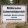 Das Bild zeigt ein Schild, das an einem Zaun in einem militärischen Sicherheitsbereich angebracht ist. Es warnt vor unbefugtem Betreten und weist darauf hin, dass Schusswaffengebrauch droht.