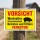 Das Bild zeigt ein gelbes Warnschild, das auf einem Holzpfosten befestigt ist. Es weist darauf hin, dass der Bereich wertvollen Schweinebestands enthält und das Betreten sowie Füttern verboten ist.