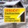Das Bild zeigt ein Warnschild mit dem Text „VORSICHT! Dachlawinen“. Es befindet sich in einem schneebedeckten Gebiet und weist darauf hin, dass das Parken und Begehen in der Nähe auf eigene Gefahr erfolgt, da von den Dächern Lawinen drohen könnten.