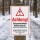 Das Bild zeigt ein Warnschild, das auf einen eingeschränkten Winterdienst hinweist. Es steht in einem verschneiten Waldgebiet und fordert Passanten auf, den Bereich auf eigene Gefahr zu betreten.
