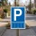 Das Bild zeigt ein Parkplatzschild mit einem großen weißen „P“ auf blauem Hintergrund. Es steht auf einem Holzpfahl am Straßenrand und weist darauf hin, dass hier Parkmöglichkeiten für Fahrzeuge vorhanden sind.