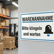 Das Bild zeigt ein Schild mit der Aufschrift Warenannahme in großen, schwarzen Buchstaben. Darunter steht Bitte klingeln und warten, begleitet von einem Symbol einer Glocke, und das Schild ist in einem Lagerbereich angebracht, wo Waren entgegengenommen werden.