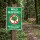 Das Bild zeigt ein Schild mit der Aufschrift Wald gesperrt! in großen, weißen Buchstaben auf grünem Hintergrund. Es warnt davor, den Wald zu betreten, da Lebensgefahr besteht, und ist an einem Waldweg aufgestellt, der von einem Seil abgesperrt ist, während im Hintergrund Holzstämme gelagert sind.