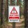 Das Bild zeigt ein Warnschild, das auf die Allergiegefahr durch den Kiefern-Prozessionsspinner hinweist. Es steht in einem Waldgebiet und ist gut sichtbar, um Passanten vor möglichen gesundheitlichen Risiken zu warnen.