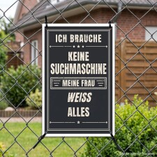 Das Bild zeigt ein Schild, das an einem Zaun hängt. Es trägt den humorvollen Text „Ich brauche keine Suchmaschine, meine Frau weiß alles“ und ist in einem schwarz-weißen Design gehalten, was es auffällig und leicht lesbar macht.